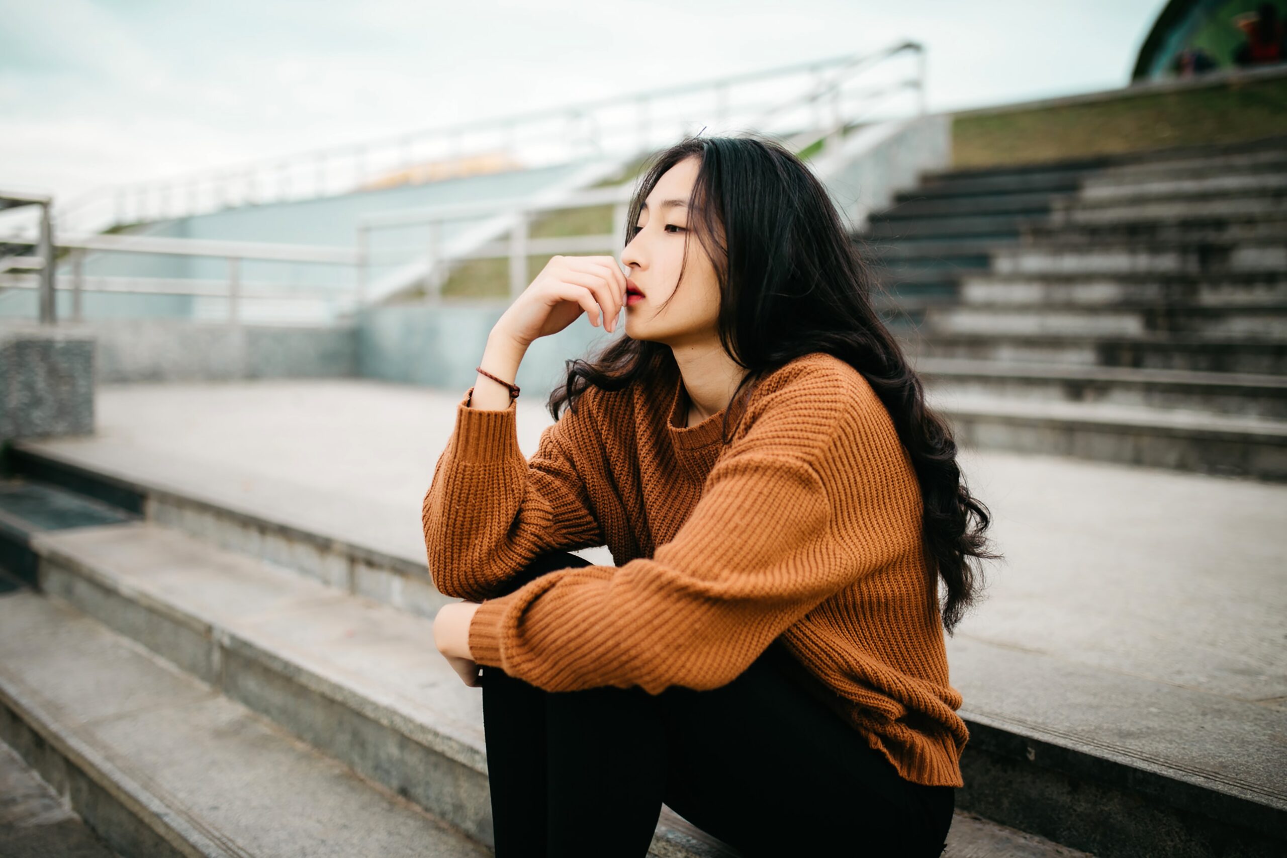 Asian woman sitting on outdoor stadium stairs thinking