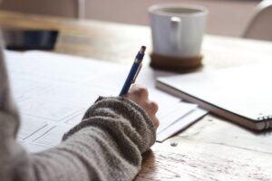 Female writing down her autoimmune disease symptoms and medication side effects