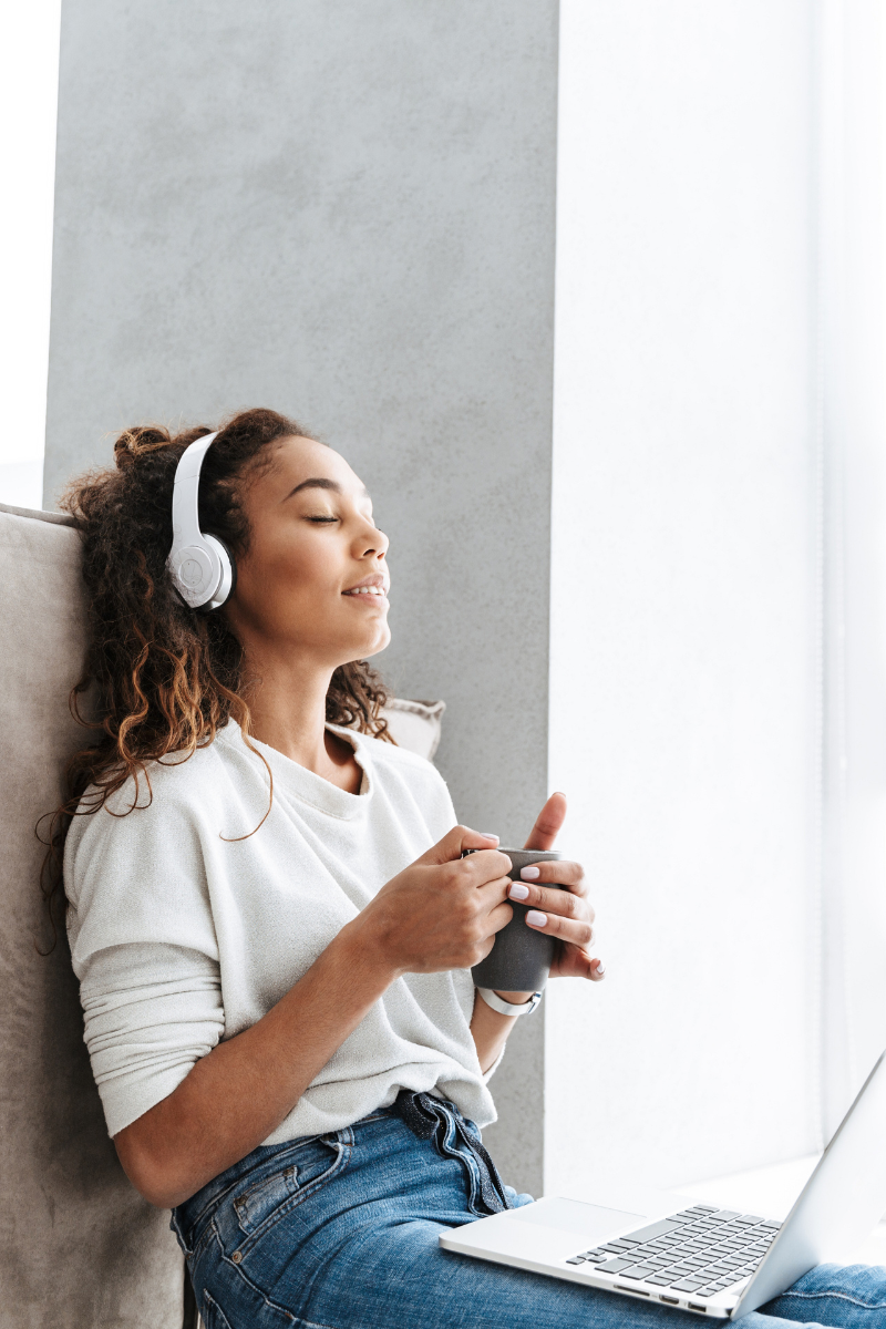 A woman wearing headphones, immersed in listening to binaural beats for focus. She appears calm and focused, highlighting the benefits of sound therapy for concentration and mental clarity. The image is featured in a blog post on the Invigorate Your Journey Blog.