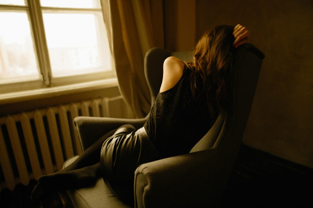 A person is slumped in a chair, fast asleep with their head tilted to one side, reflecting a deep sense of exhaustion and fatigue. The disheveled posture conveys the struggle to stay awake amid overwhelming tiredness. Soft lighting surrounds them, emphasizing the need for rest and the toll that fatigue takes on daily life.