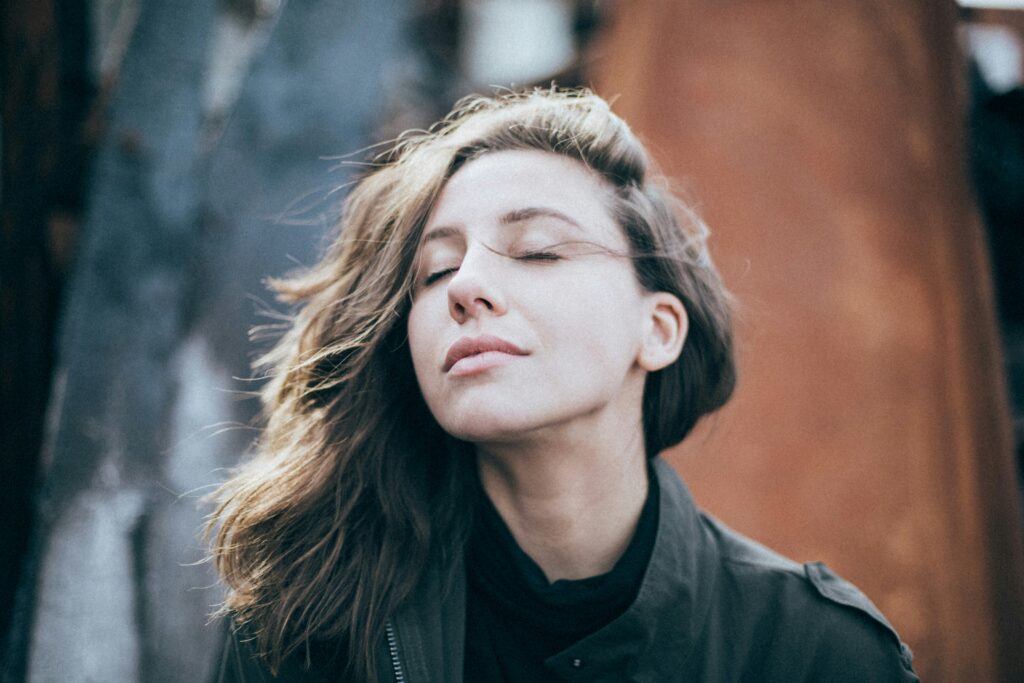 Relaxed woman with eyes closed, practicing deep breathing to boost energy and focus—part of simple, science-backed strategies to beat the afternoon slump.